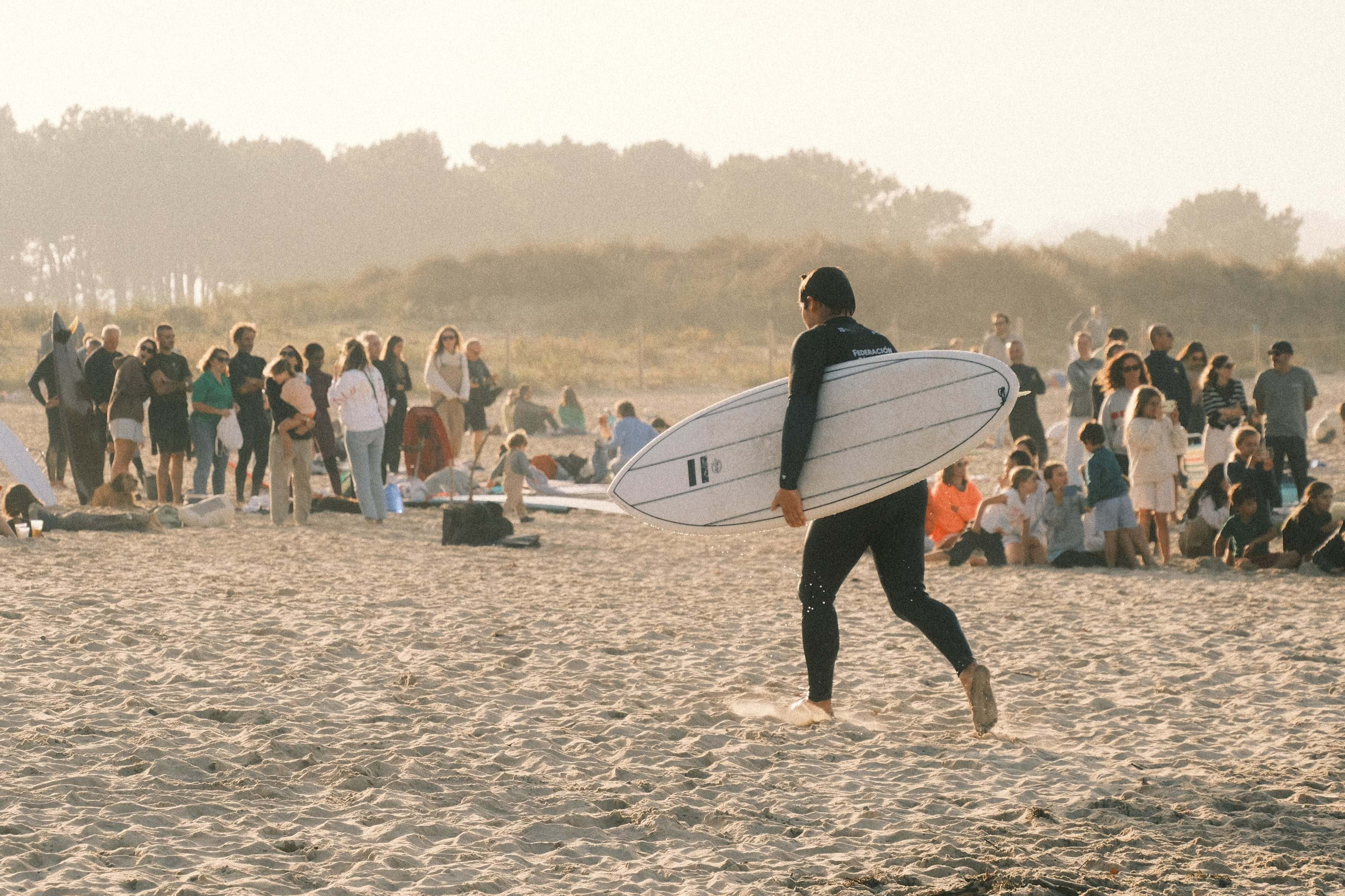 Surfer carrying a board past spectators at a surf contest